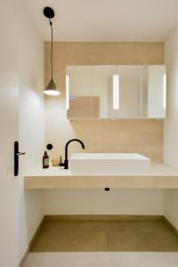 a white kitchen with a sink and a mirror at Le Splendide de Poincaré in Nancy