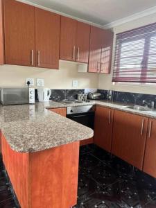 a kitchen with wooden cabinets and a granite counter top at Wood Road Apartments in Durban