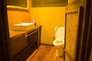 La salle de bains est pourvue de toilettes blanches et d'un lavabo. dans l'établissement Queen Elizabeth Bush Lodge by NATURE LODGES LTD, à Bushenyi