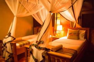 a bedroom with two beds with mosquito nets at Queen Elizabeth Bush Lodge by NATURE LODGES LTD in Bushenyi