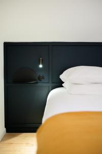 łóżko z czarnym zagłówkiem i białymi poduszkami w obiekcie Le Splendide de Poincaré w Nancy