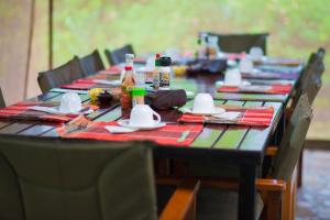 una mesa larga con botellas y servilletas. en Queen Elizabeth Bush Lodge by NATURE LODGES LTD, en Bushenyi