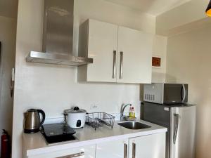 a kitchen with white cabinets and a stainless steel refrigerator at Great 1BR Aqua Livingstone with Netflix, Pool & Gym in Manila