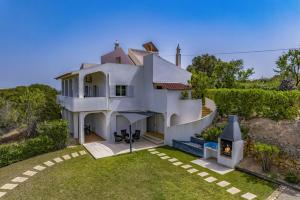 a white house with a fireplace in the yard at Villa Alfarrobeira by Villa Plus in Lagoa