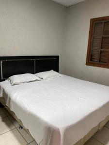 a large white bed in a room with a window at Casa com piscina in Armacao dos Buzios