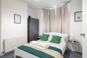 a bedroom with a bed with green and white pillows at LiveStay - 5 Bedroom House in Stratford in London