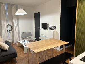 uma sala de estar com uma mesa e um sofá em Appartement au centre-ville à 100 m des télécabines avec parking souterrain gratuit em Luchon