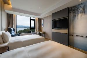 um quarto de hotel com duas camas e uma televisão de ecrã plano em Atour Hotel Hangzhou Qiandao Lake Central Dock em Chun'an