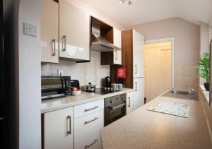 a kitchen with white cabinets and a sink and a microwave at 4 Bedroom Apartment with Essentials - free private parking, private check-in and check-out and free WiFi in Lincolnshire