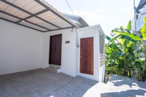 a small white house with a wooden door at The Lavana De Mello's Villa Seminyak -1 Bedroom Villa with Private Pool in Kerobokan