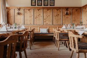 シェッファウ・アム・ヴィルデン・カイザーにあるHotel Kaiser in Tirolの木製の壁と木製のテーブルと椅子が備わるレストラン