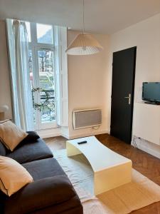 a living room with a couch and a table at Appartement au centre-ville à 100 m des télécabines avec parking souterrain gratuit in Luchon