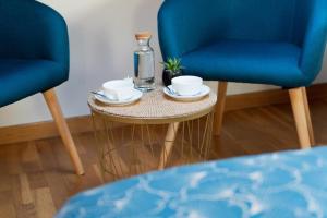 Dos sillas azules y una mesa con dos tazas y una botella. en Hostal Pension Artilleiro, en Santiago de Compostela