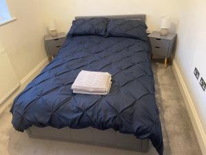 a bed with a blue comforter and two night stands at 3 swallow close IDEAL FOR CONTRACTORS , FAMILIES AND WEEKEND STAYS in Olney