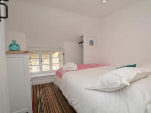 a white bedroom with a bed and a window at 2 Bed in Burton Bradstock DC166 in Burton Bradstock