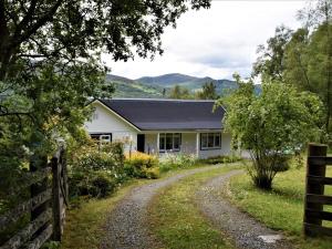 uma casa branca com uma cerca e uma estrada de terra em 2 Bed in Pitlochry CA084 em Struan