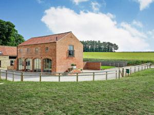 a brick building with a fence next to a field at 3 Bed in Malton 75898 in Amotherby