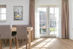 una sala da pranzo con tavolo, sedie e porte scorrevoli in vetro di Summio Villaparc Schoonhovenseland a Hollandscheveld