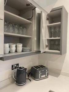 a kitchen counter with a toaster and dishes on shelves at 3 swallow close IDEAL FOR CONTRACTORS , FAMILIES AND WEEKEND STAYS in Olney