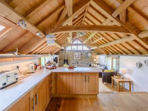 a large kitchen with wooden cabinets and a ceiling with beams at 2 Bed in Umberleigh 74967 in Chittlehampton