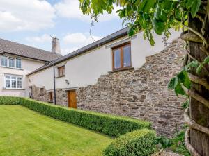 a house with a stone wall and a yard at 2 Bed in Umberleigh 74967 in Chittlehampton