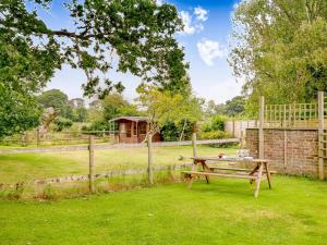 a wooden picnic table in a field with a fence at 3 Bed in Stoborough DC157 in Stoborough