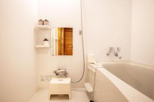 a white bathroom with a toilet and a bath tub at Ecommodation 百のやど in Aone