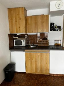 eine Küche mit Holzschränken und einer Mikrowelle in der Unterkunft Appartement Saint Lary Soulan Pla d Adet pied des pistes capacité 5pers in Saint-Lary-Soulan