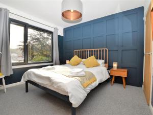 Dormitorio azul con cama con almohadas amarillas en 3 Bed in Pitlochry CA207, en Struan