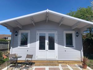 a white tiny house with a porch and a table at Bijou Bunker in Whitstable