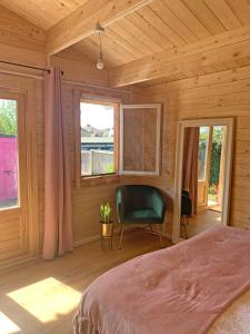 a bedroom with a bed and a chair and windows at Bijou Bunker in Whitstable