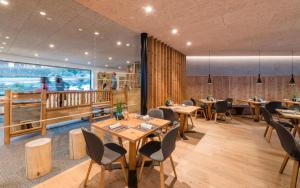 um restaurante com mesas e cadeiras de madeira e uma grande janela em Hotel Lener em Campo di Trens
