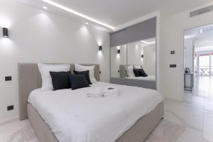 L'unique Maubourg - Next Hotel Martinez - Terrasse في كان: غرفة نوم بيضاء مع سرير كبير عليها منشفتين