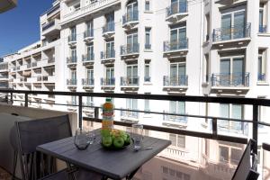 L'unique Maubourg - Next Hotel Martinez - Terrasse في كان: طاولة مع كؤوس النبيذ والفواكه على الشرفة