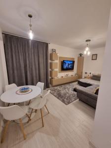 sala de estar con mesa, sillas y sofá en Daric Residence Apartaments, en Fălticeni