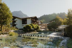 um resort com um lago em frente a um edifício em Hotel Kaiser in Tirol em Scheffau am Wilden Kaiser