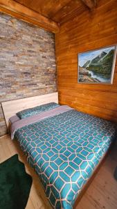 a bed in a room with a wooden wall at Eko kuća Zlatiborsko srce in Zlatibor