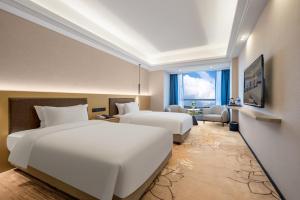 a hotel room with two beds and a living room at Jiayu Hotel - Guangzhou Baiyun International Airport T2 Terminal in Huadu