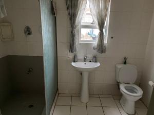 La salle de bains est pourvue d'un lavabo, de toilettes et d'une fenêtre. dans l'établissement 4 Bedroom Family Home, à Port Elizabeth