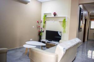 a living room with a couch and a table and a tv at Fully Furnished 1- Bedroom in East Legon in Madina