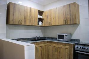 cocina con armarios de madera y microondas en Fully Furnished 1- Bedroom in East Legon en Madina