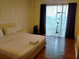 a bedroom with a large bed and a large window at Golden Dragon Resort in Sing Buri