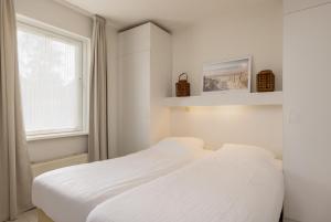 two beds in a white room with a window at Summio Vakantiepark It Wiid in Earnewâld