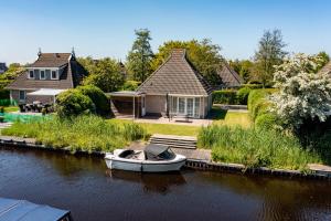a boat is docked in the water next to a house at Summio Vakantiepark It Wiid in Earnewâld