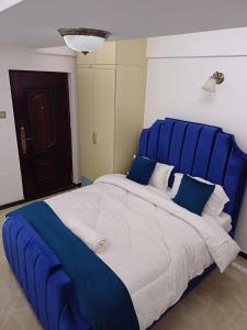 a large blue bed with white and blue pillows at Studio Apartment in Nairobi