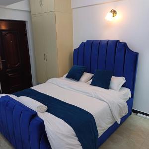 a large bed with a blue headboard in a room at Studio Apartment in Nairobi
