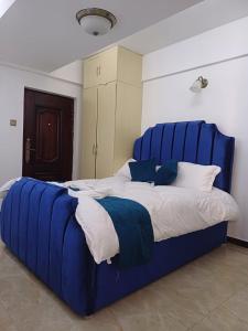 a large bed with a blue headboard in a room at Studio Apartment in Nairobi