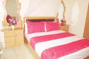 Schlafzimmer mit einem Bett mit rosa Bettwäsche und Kissen in der Unterkunft Nallur Mylooran Arangam in Jaffna