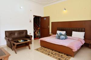 a bedroom with a large bed and a chair at Hotel Vasundhara Palace in Chamba