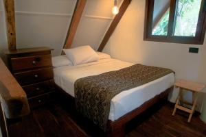 a small bedroom with a bed and a window at Cabaña Chechen, wooden chalet in tropical garden in Isla Mujeres